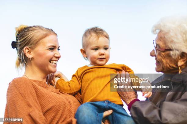 niño saltando con madre y abuela jugando juntos al aire libre en el patio a fines del verano y principios de otoño serie de fotos - bisnieto fotografías e imágenes de stock