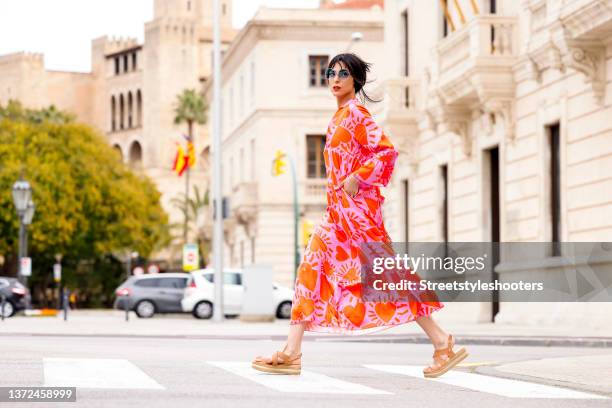 Model Zoe Helali wearing a pink and orange heart print maxi summer dress by Miss Goodlife, vintage nude sandals, blue tinted geometric sunglasses by...