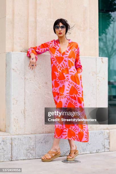 Model Zoe Helali wearing a pink and orange heart print maxi summer dress by Miss Goodlife, vintage nude sandals, blue tinted geometric sunglasses by...