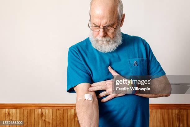 colorectal cancer survivor looking down at blood test bandage - colorectal cancer screening stock pictures, royalty-free photos & images