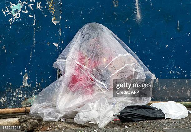 Drug addict protects from the rain with a plastic bag to smoke crack cocaine in a street of "Cracolandia" , in downtown Sao Paulo, Brazil on January...