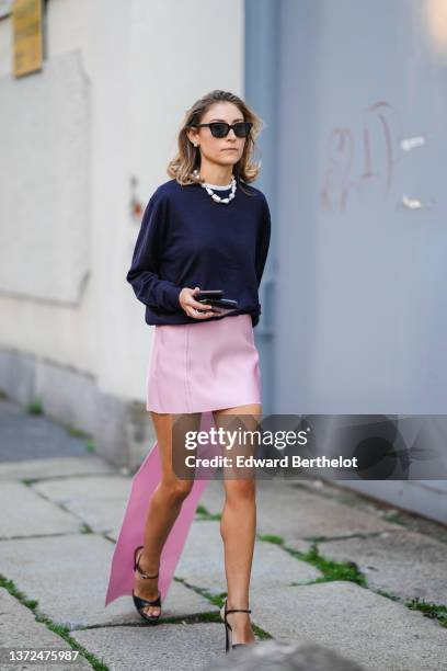 Jenny Walton wears black sunglasses, pearl earrings, a large pearls necklace, a black puffy sleeves pullover, a silver and diamonds ring, a black...