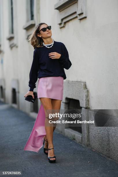 Jenny Walton wears black sunglasses, pearl earrings, a large pearls necklace, a black puffy sleeves pullover, a silver and diamonds ring, a black...