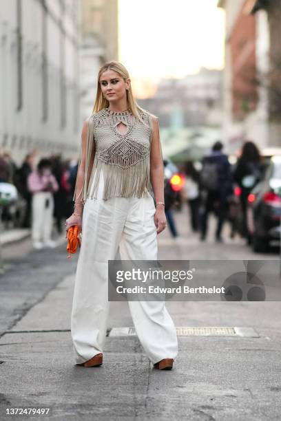 Valentina Ferragni wears gold earrings, a neon green earrings, a gold large chain necklace, a beige braided macrame cut-out / fringed sleeveless...