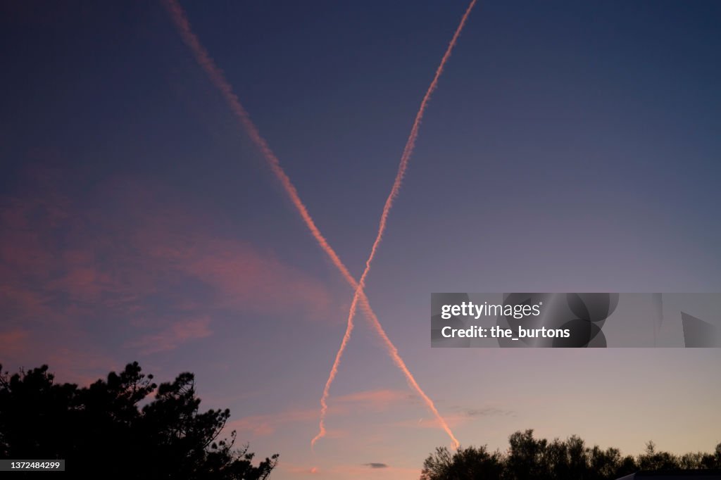 Low angle view of vapor trails during sunset