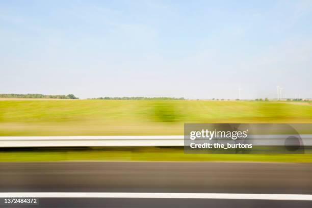 blurred sideview out of car`s window on crash barrier and landscape on a motorway - crash barrier stock pictures, royalty-free photos & images