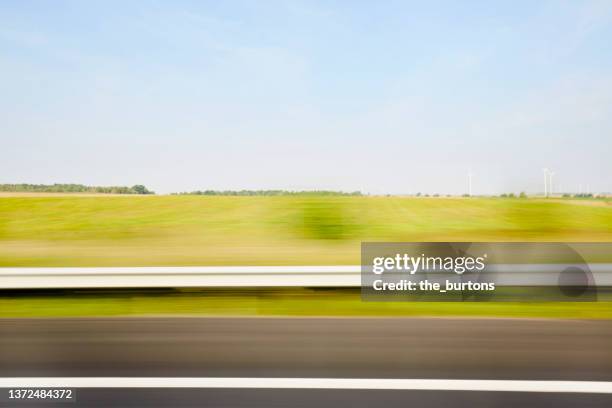 blurred sideview out of car`s window on crash barrier and landscape on a motorway - vägräcke bildbanksfoton och bilder