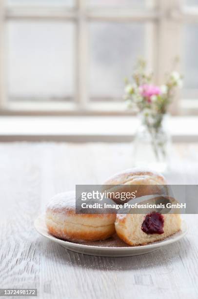 jam doughnuts on a plate next to a window - beignet fourré photos et images de collection