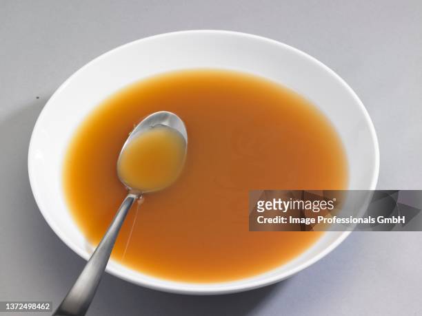 a bowl of chicken broth with a spoon - hühnerbrühe stock-fotos und bilder