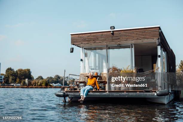 senior man relaxing at houseboat on sunny day - hausboot stock-fotos und bilder
