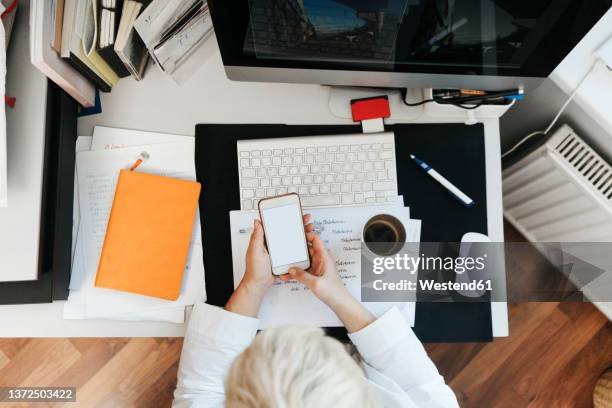 woman surfing net through smart phone on desk - curator stock pictures, royalty-free photos & images