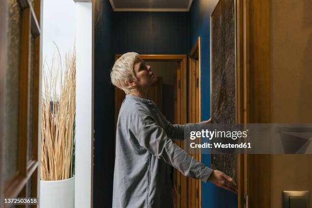 woman hanging picture frame on wall at home - art dealer stock pictures, royalty-free photos & images