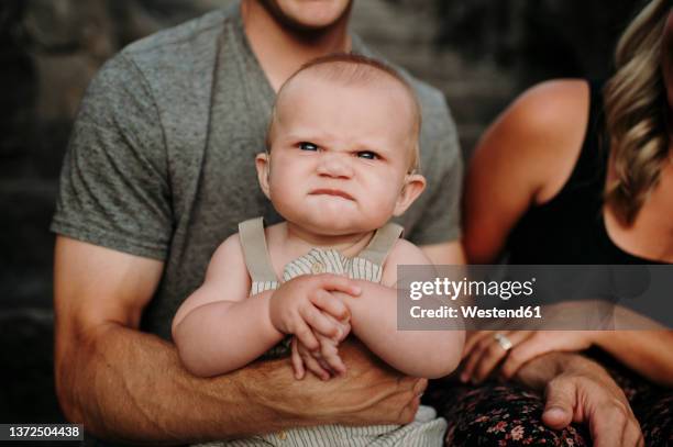 baby boy making funny face sitting with parents - funny baby face stock pictures, royalty-free photos & images