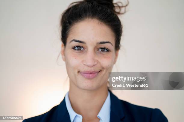 beautiful businesswoman smirking in front of wall - haarknoten stock-fotos und bilder