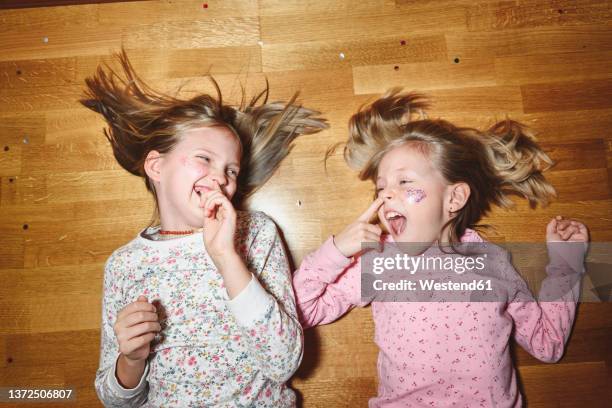 sisters picking noses at each other lying down laughing on floor - picarse la nariz fotografías e imágenes de stock