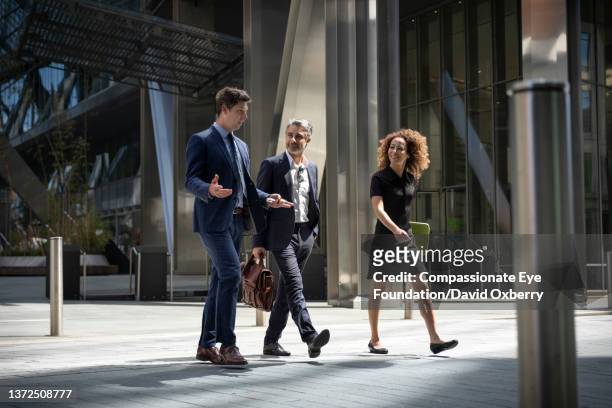 coworkers walking and talking in the city - business suits discussion stock-fotos und bilder