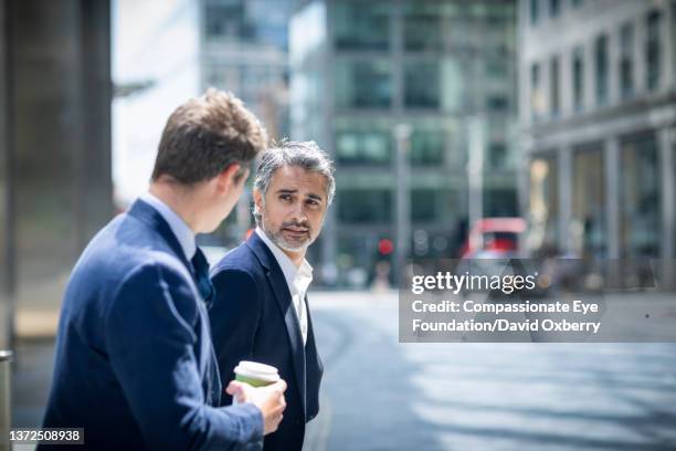two businessmen walking and talking in city - conversation car bildbanksfoton och bilder