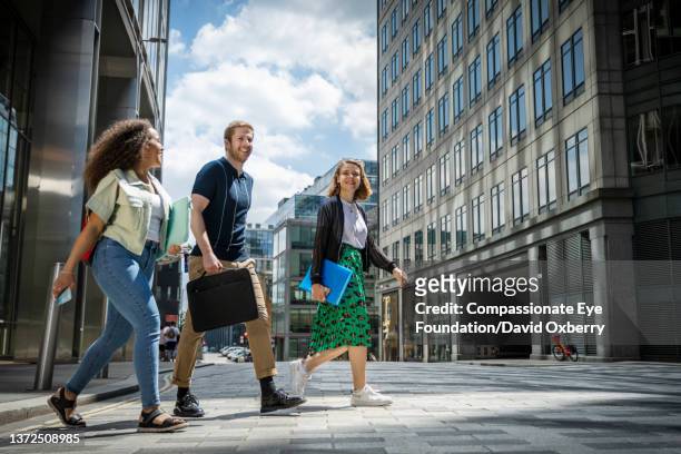 coworkers walking and talking in the city - group of friends walking along street fotografías e imágenes de stock