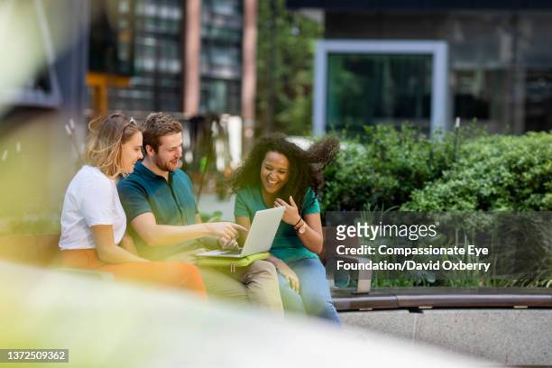 coworkers discussing project outside - werk laptop buiten stockfoto's en -beelden