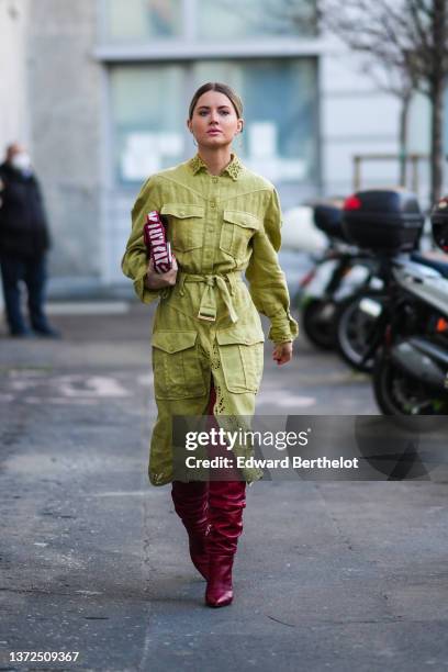 Julia Tiberio wears gold earrings, a green denim with lace print pattern collar and borders / belted cargo slit / split midi dress, a red and white...