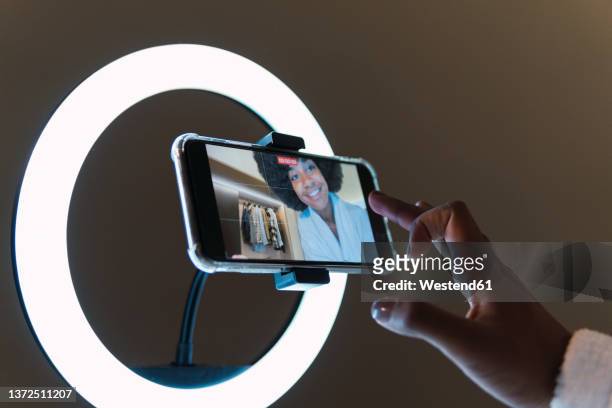smiling woman vlogging on smart phone in illuminated ring light - influencer fotografías e imágenes de stock
