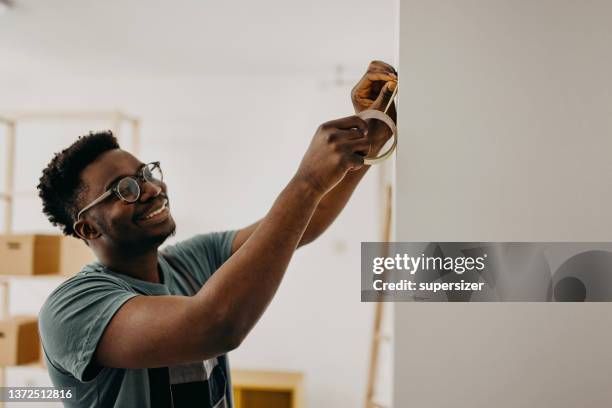 afroamerikanischer professioneller maler malt die wand drinnen - klebeband stock-fotos und bilder