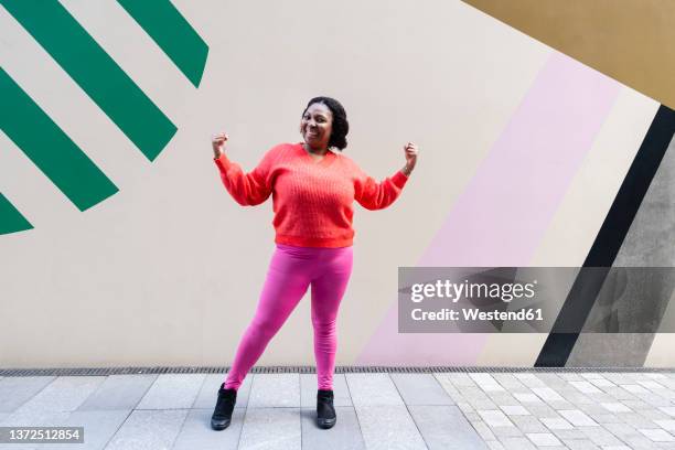 smiling woman flexing muscles in front of wall - gouvernement photos et images de collection