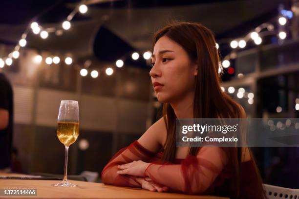 young asian woman feeling sad and heartbroken after breaking up with her boyfriend while sitting at restaurant - pessimism stock pictures, royalty-free photos & images