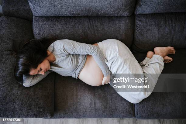 pregnant woman lying on sofa at home - lying on side stock pictures, royalty-free photos & images