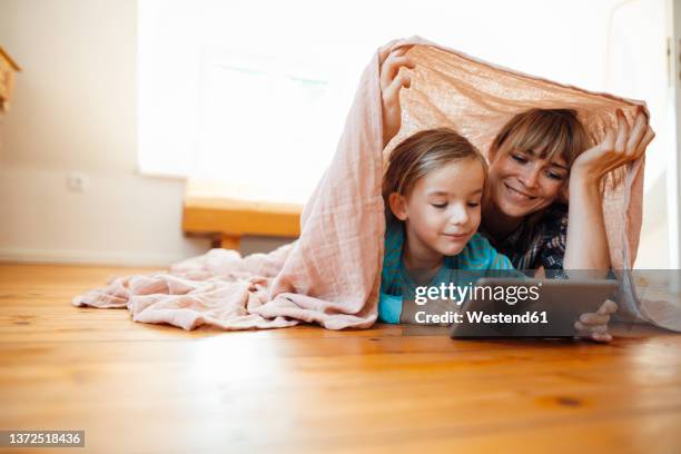 mother and son below shawl watching tablet pc at home - lying on front stock pictures, royalty-free photos & images