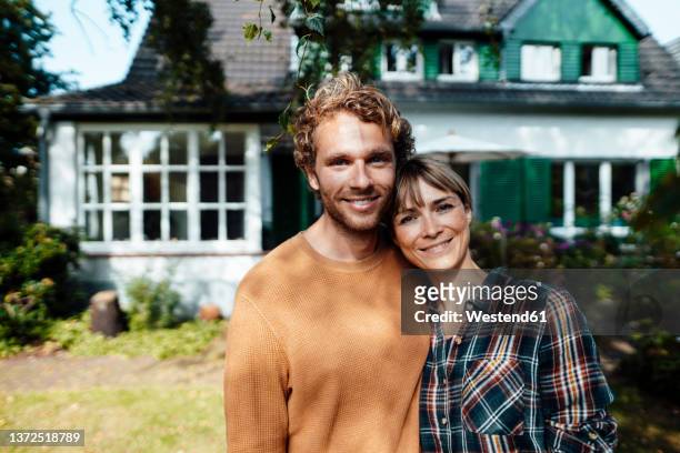 smiling couple standing outside house - couple house stockfoto's en -beelden