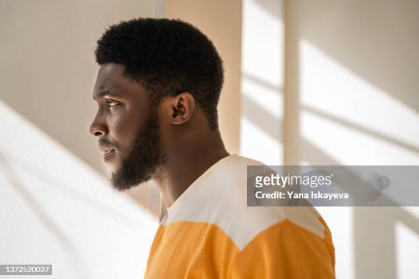side portrait of a young and handsome african american black man looking at the window - zwart stockfoto's en -beelden