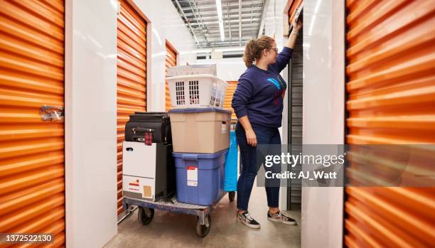 donna che conserva i suoi effetti personali in unità di self storage - scompartimento di immagazzinaggio foto e immagini stock