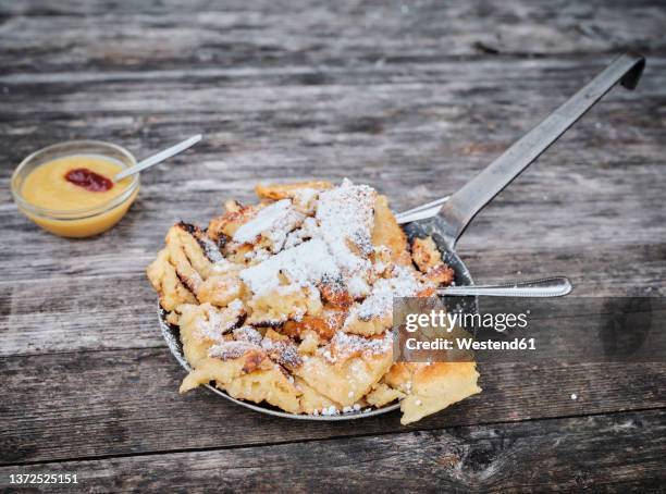 kaiserschmarren served in cooking pan by apple sauce on wooden table - kaiserschmarrn stock pictures, royalty-free photos & images