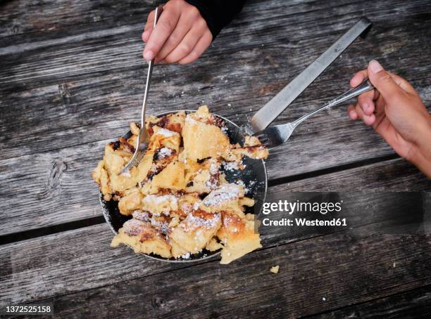 boy and girl with fork taking kaiserschmarrn on wooden table - kaiserschmarrn stock pictures, royalty-free photos & images