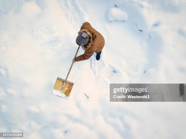 man cleaning snow with snow shovel in winter - excavar fotografías e imágenes de stock