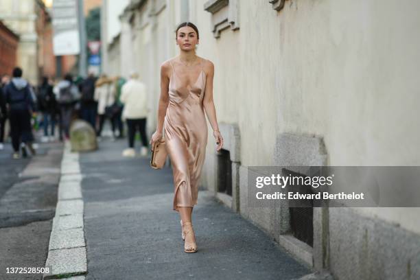 Guest wears a beige and brown leopard print pattern hair clip, gold earrings, a beige shiny silk V-neck / tank-top midi dress, a beige matte leather...