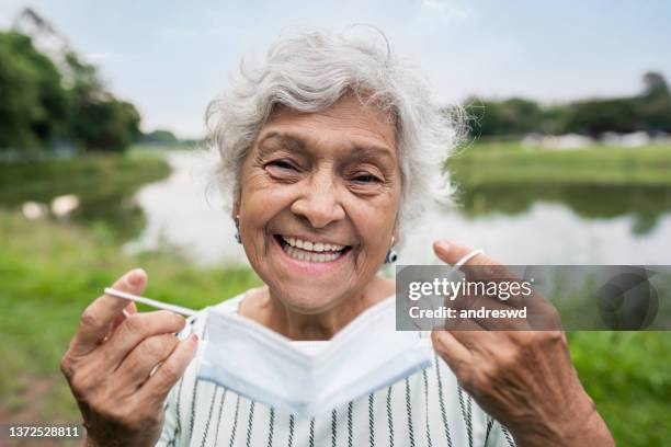 elderly woman removing covid face protection mask - end of life stock pictures, royalty-free photos & images