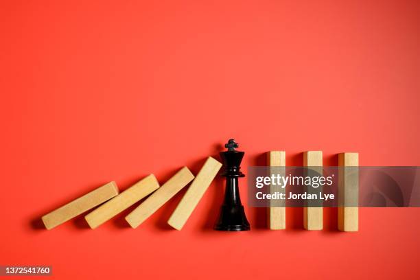 ing chess piece stopping the domino effect concept - chess concept stock pictures, royalty-free photos & images