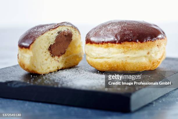 nougat doughnuts with chocolate glaze, whole and halved - beignet fourré photos et images de collection