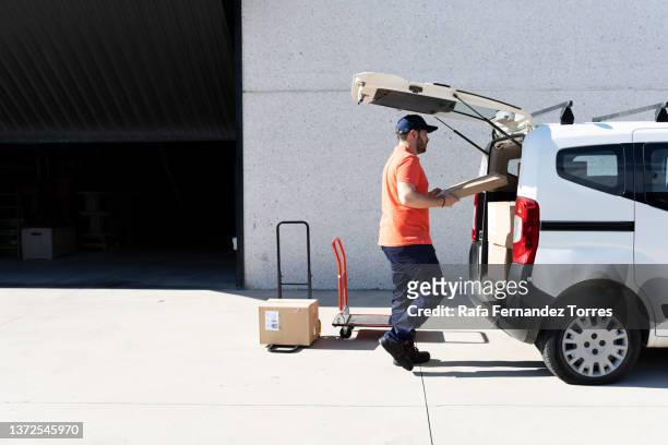 delivery man in uniform loading the truck. - lieferwagen stock-fotos und bilder