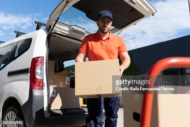 delivery man wearing uniform unloading parcel - removal men imagens e fotografias de stock