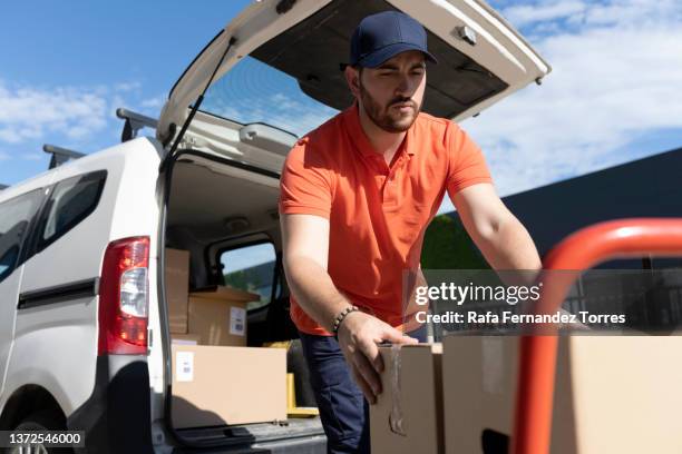 delivery man wearing uniform unloading parcel - 配達員 ストックフォトと画像