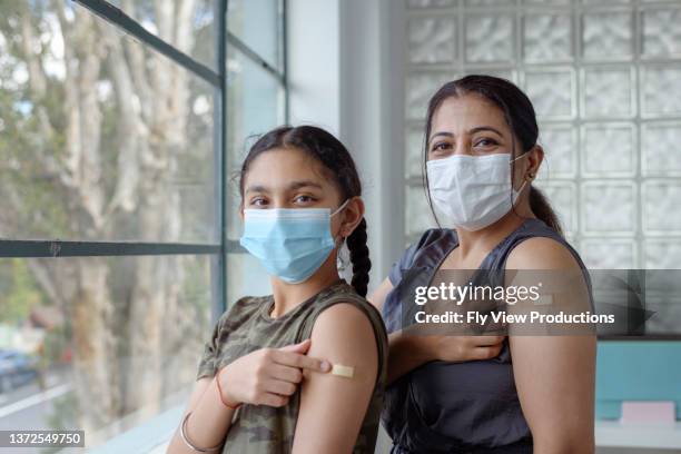 porträt einer glücklichen mutter und tochter nach der covid-19-impfung - indian girl pointing stock-fotos und bilder