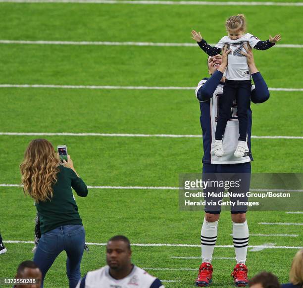 New England Patriots quarterback Tom Brady checks out the photo offensive coordinator Josh McDaniels, right, took of Brady with wife Gisele Bundchen,...