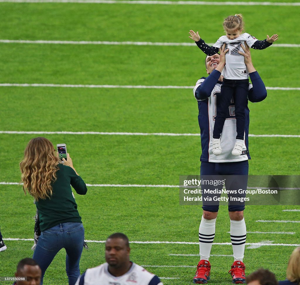 (02/04/2017- Houston, TX) New England Patriots quarterback Tom Brady checks out the photo offensive coordinator Josh McDaniels, right, took of Brady with wife Gisele Bundchen, left, daughter Vivian Lake Brady as sons Benjamin, right, and John Edwa