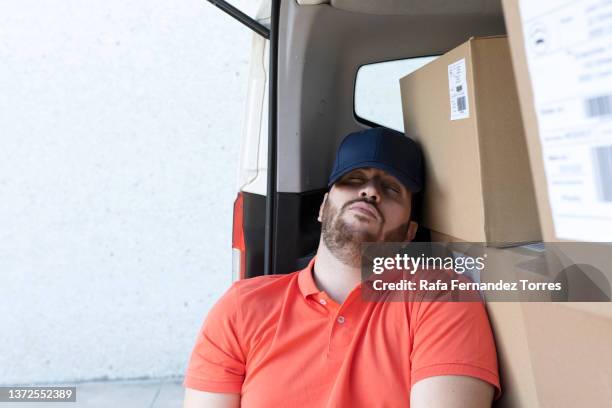 tired loader sleeping on stack of parcels - man sleeping with cap stock pictures, royalty-free photos & images
