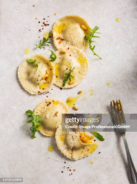 homemade pumpkin ravioli tortelloni parcels topped with pine nuts, olive oil, rocket and chilli - ravioli stock-fotos und bilder