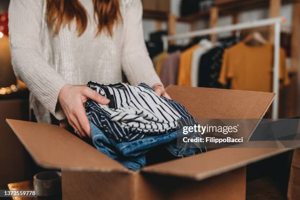 una donna millennial sta preparando la spedizione di alcuni vestiti nel suo nuovo negozio online - fashion store staff foto e immagini stock