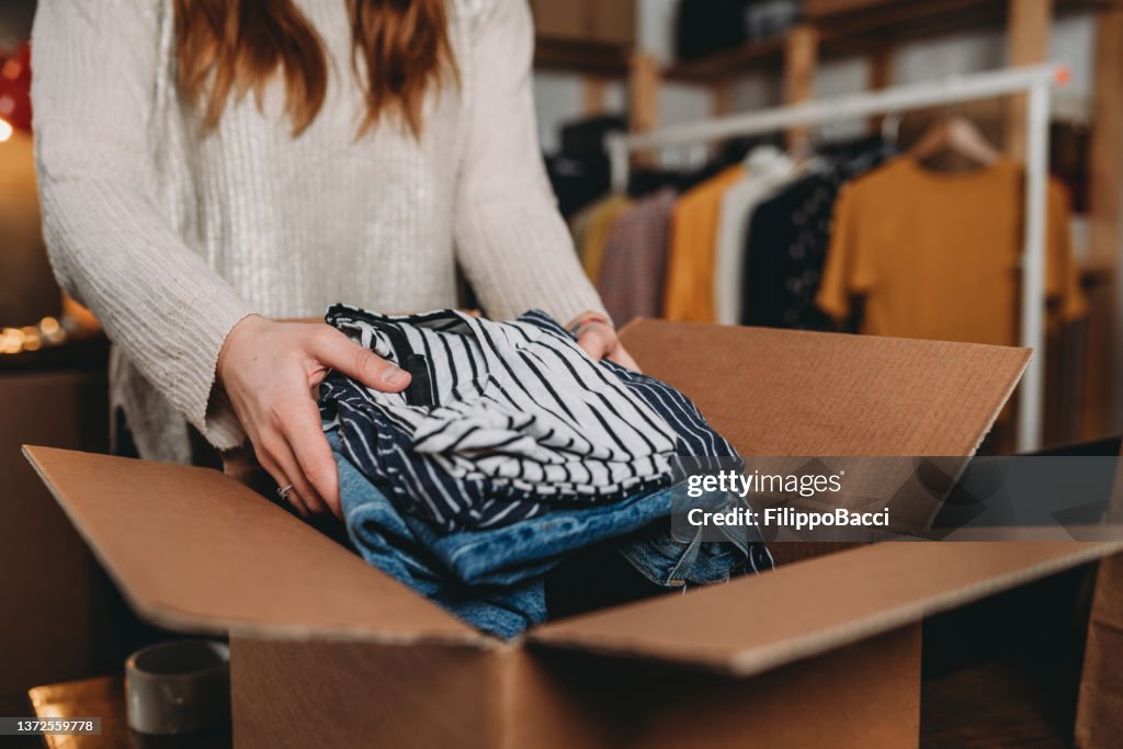 A millennial woman is preparing the shipment of some clothes in her new online shop
